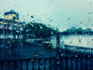 Artistic view through a rain-soaked window capturing blurred cityscape in the background.